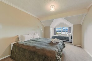 A bedroom with two beds, a large window with a view, and a ceiling light. - The Bay House - Moetapu Holiday Home (Picton)