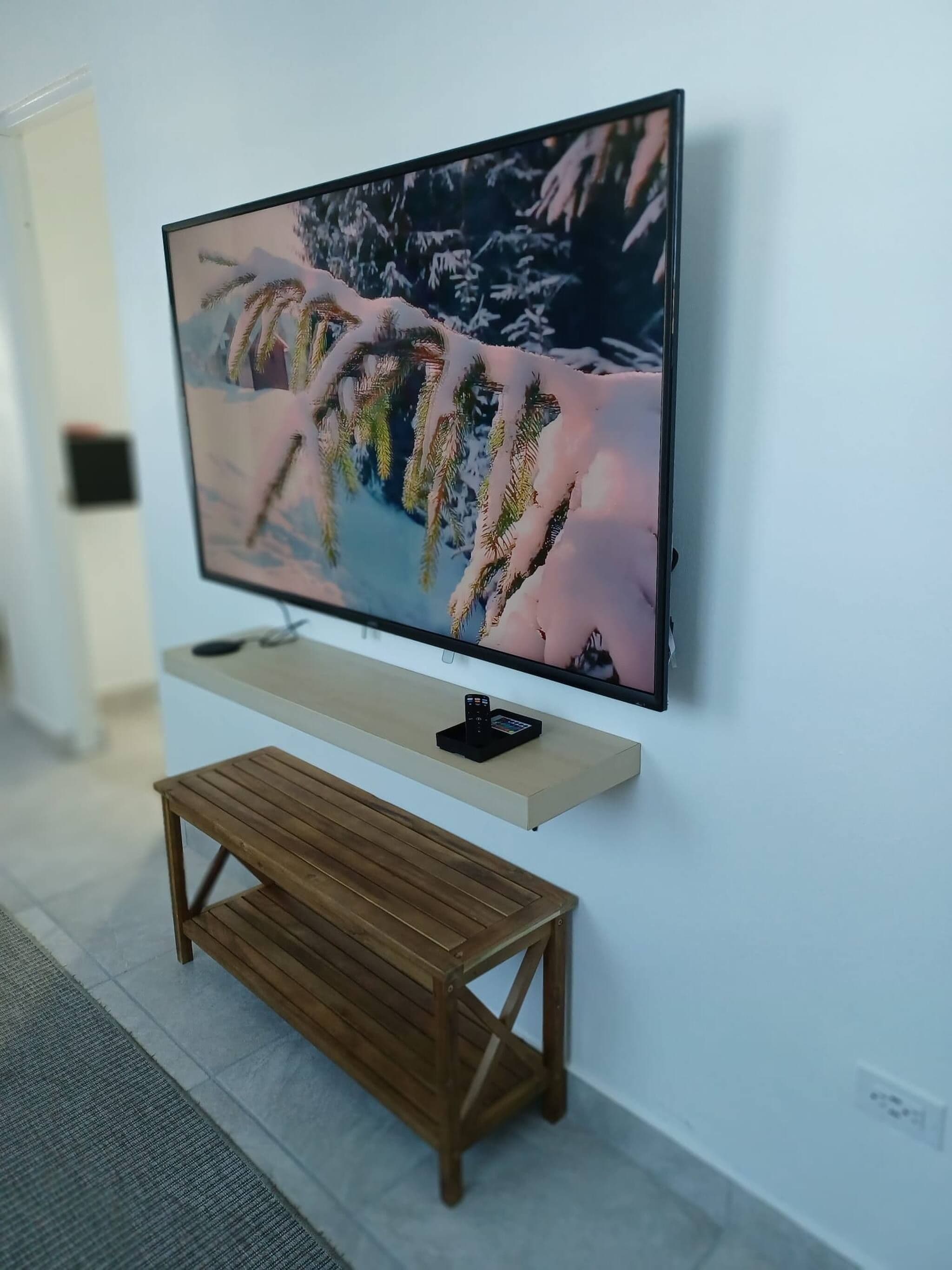 A television mounted on a wall with a wooden bench below it.