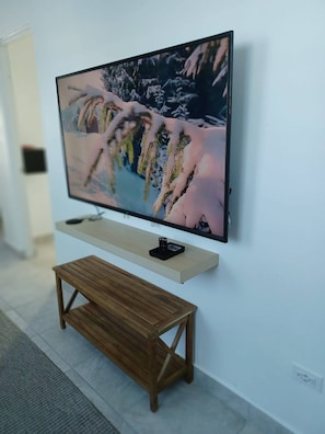 A television mounted on a wall with a wooden bench below it. - Lovely 2 Bedrooms Apartment With Terrace, Small Pool Share (San Juan)