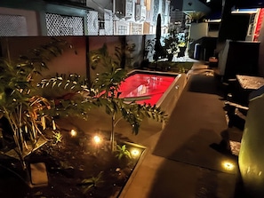 A nighttime outdoor area with a red pool, potted plants, and a pathway. - Lovely 2 Bedrooms Apartment With Terrace, Small Pool Share (San Juan)