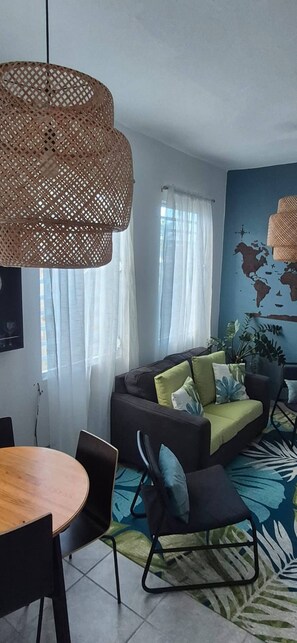 A living room with a sofa, chairs, a dining table, and a world map on the wall. - Lovely 2 Bedrooms Apartment With Terrace, Small Pool Share (San Juan)