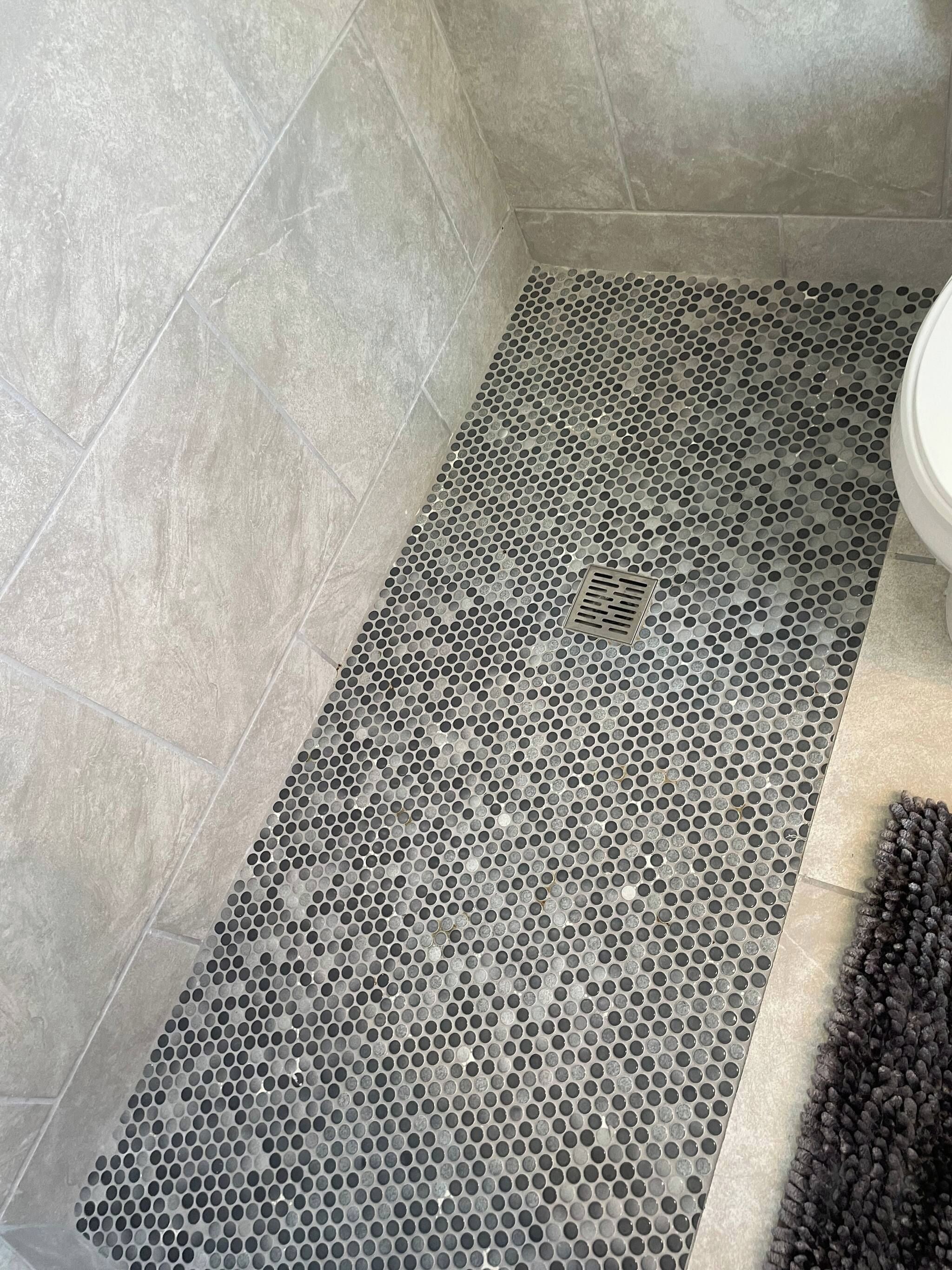 Un bagno con pavimento piastrellato, cabina doccia e servizi igienici.
