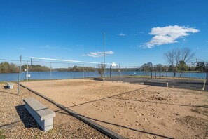 A volleyball court with a net, benches, and a basketball hoop by a lake. - Emerald Isle Condo - 2bed/2bath Lots of Amenities! (Hot Springs)