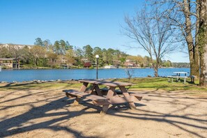 A picnic table with benches in a park setting by a lake. - Emerald Isle Condo - 2bed/2bath Lots of Amenities! (Hot Springs)