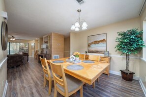 A dining area with a wooden table, chairs, and a chandelier. - Emerald Isle Condo - 2bed/2bath Lots of Amenities! (Hot Springs)