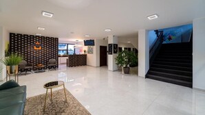 A hotel lobby with a reception desk, seating area, staircase, and potted plants. - 111Apartments (Košický kraj)