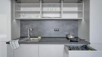 A kitchen with a built-in sink, a countertop, and a drawer with utensils.