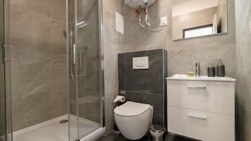 A modern bathroom with a glass-enclosed shower, a toilet, and a vanity with a mirror.