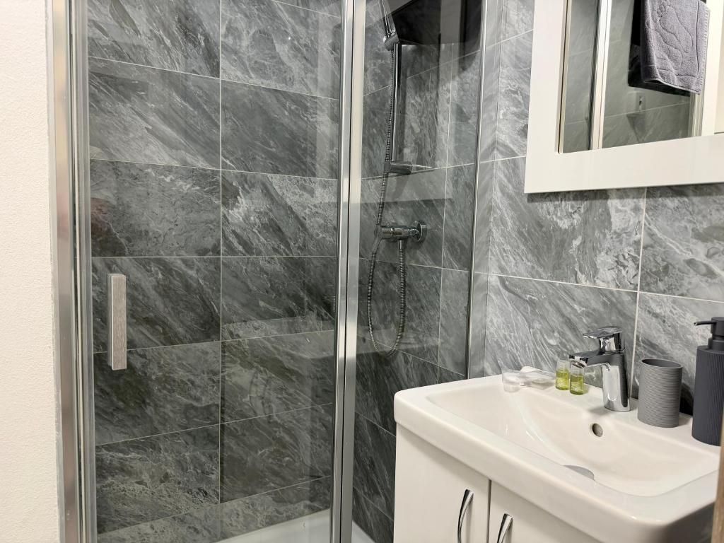 A bathroom with a glass-enclosed shower, a white sink, and a mirror above the sink.