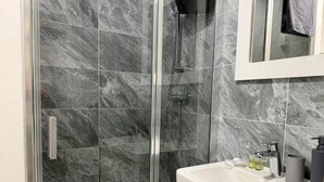 A bathroom with a glass-enclosed shower, a white sink, and a mirror above the sink. - 111Apartments (Košický kraj)