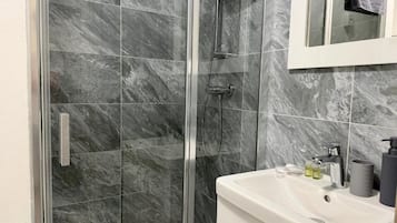 A bathroom with a glass-enclosed shower, a white sink, and a mirror above the sink.