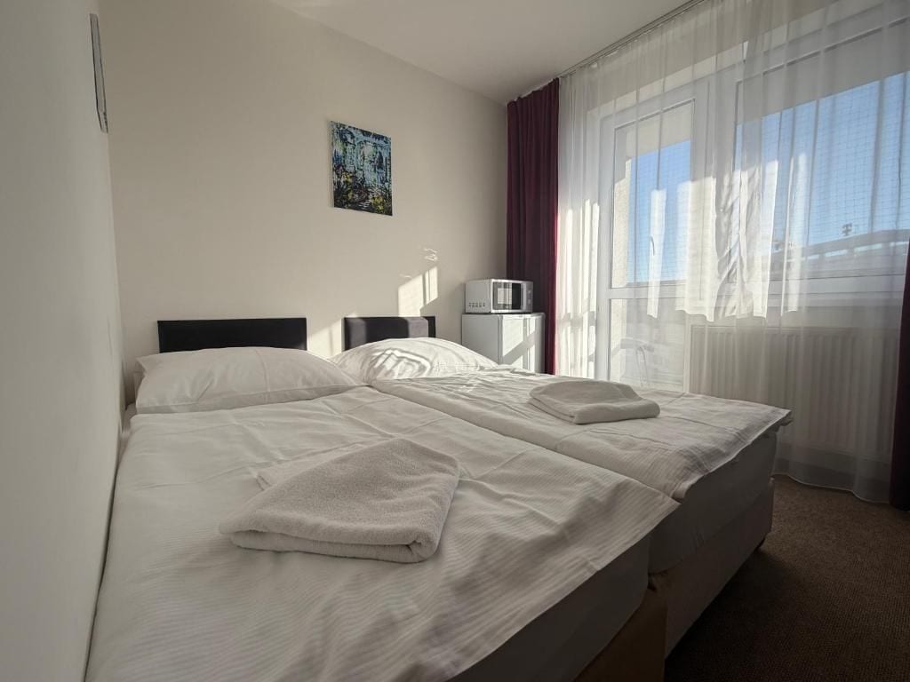 A hotel room with a bed, a flat-screen TV, a microwave, and a window with curtains.