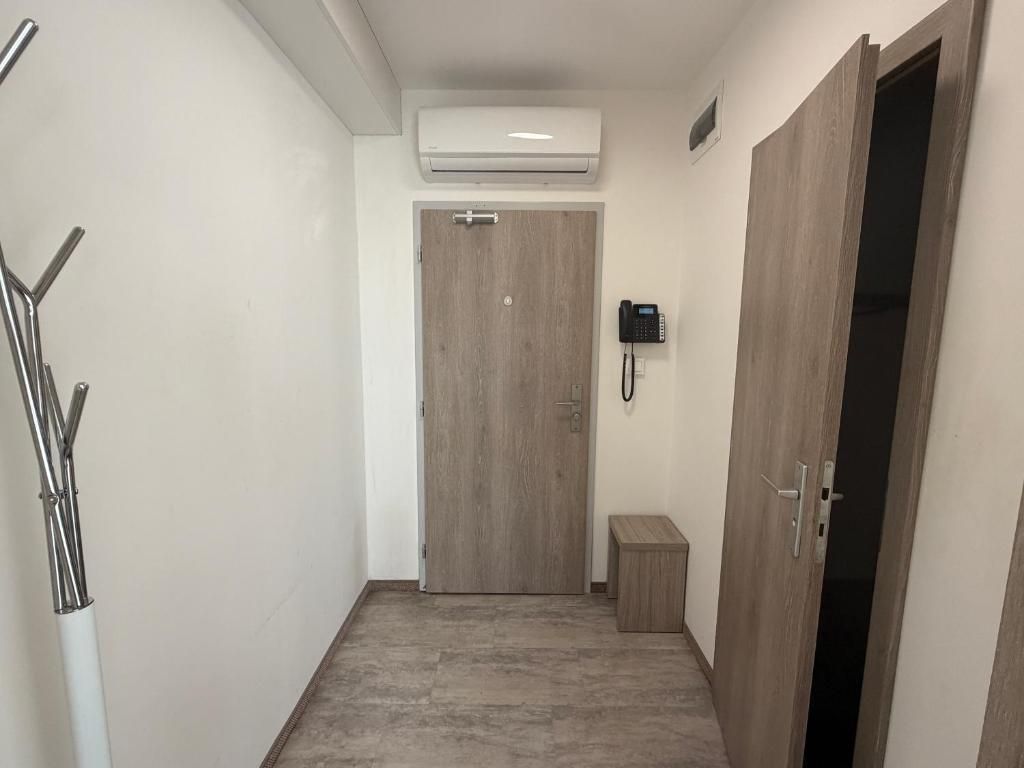 A hallway with a wooden door, a small bench, and a telephone on the wall.
