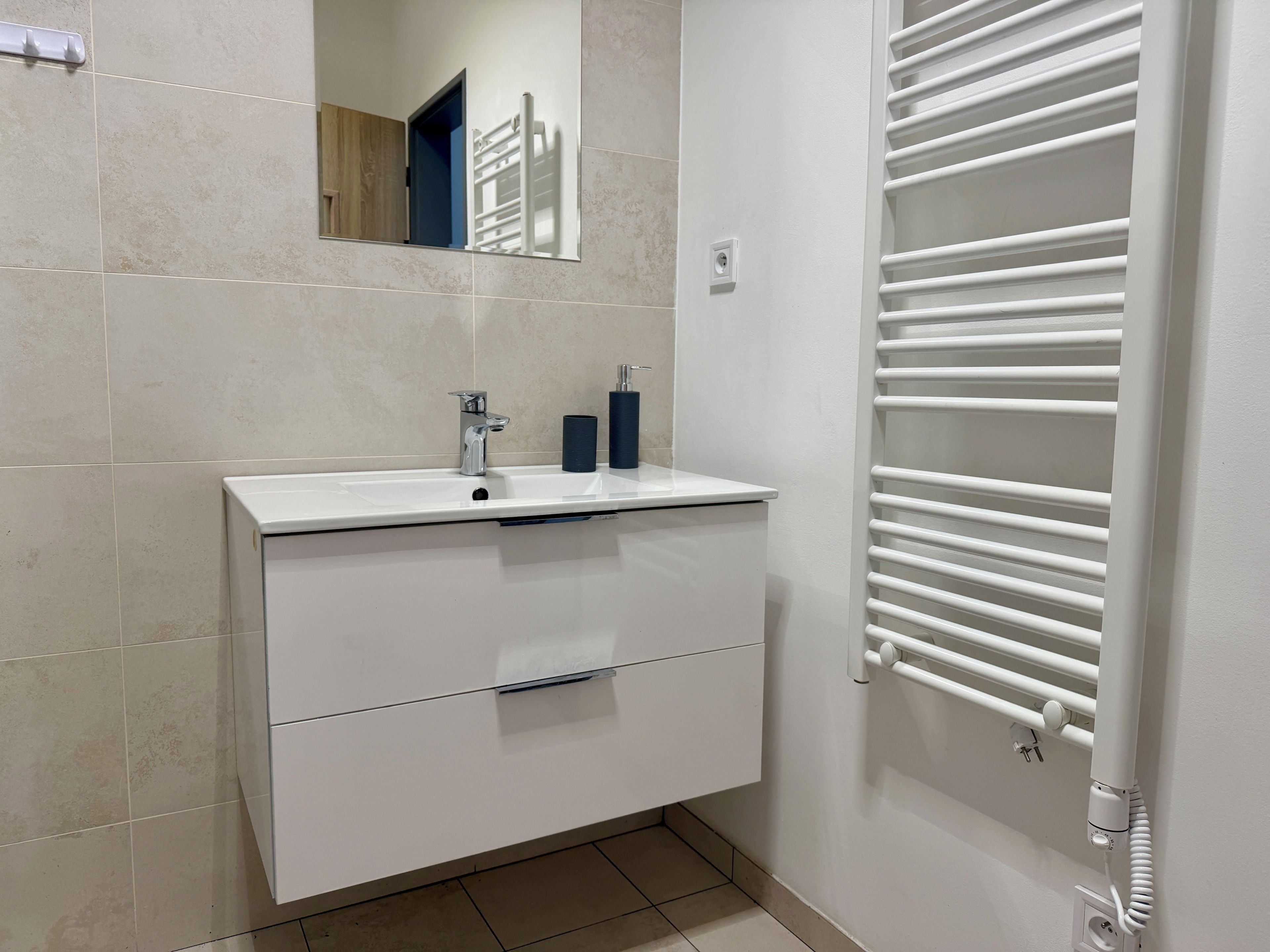 A bathroom with a white sink, mirror, and towel rack.