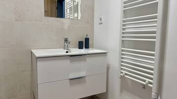 A bathroom with a white sink, mirror, and towel rack.
