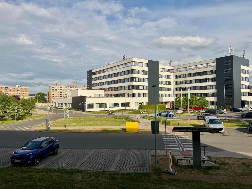 Un edificio moderno con varios pisos, estacionamiento y cielo despejado.