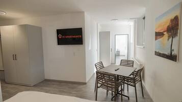 Un appartement moderne doté d’un coin repas, d’un téléviseur fixé au mur et d’un tableau accroché au mur.