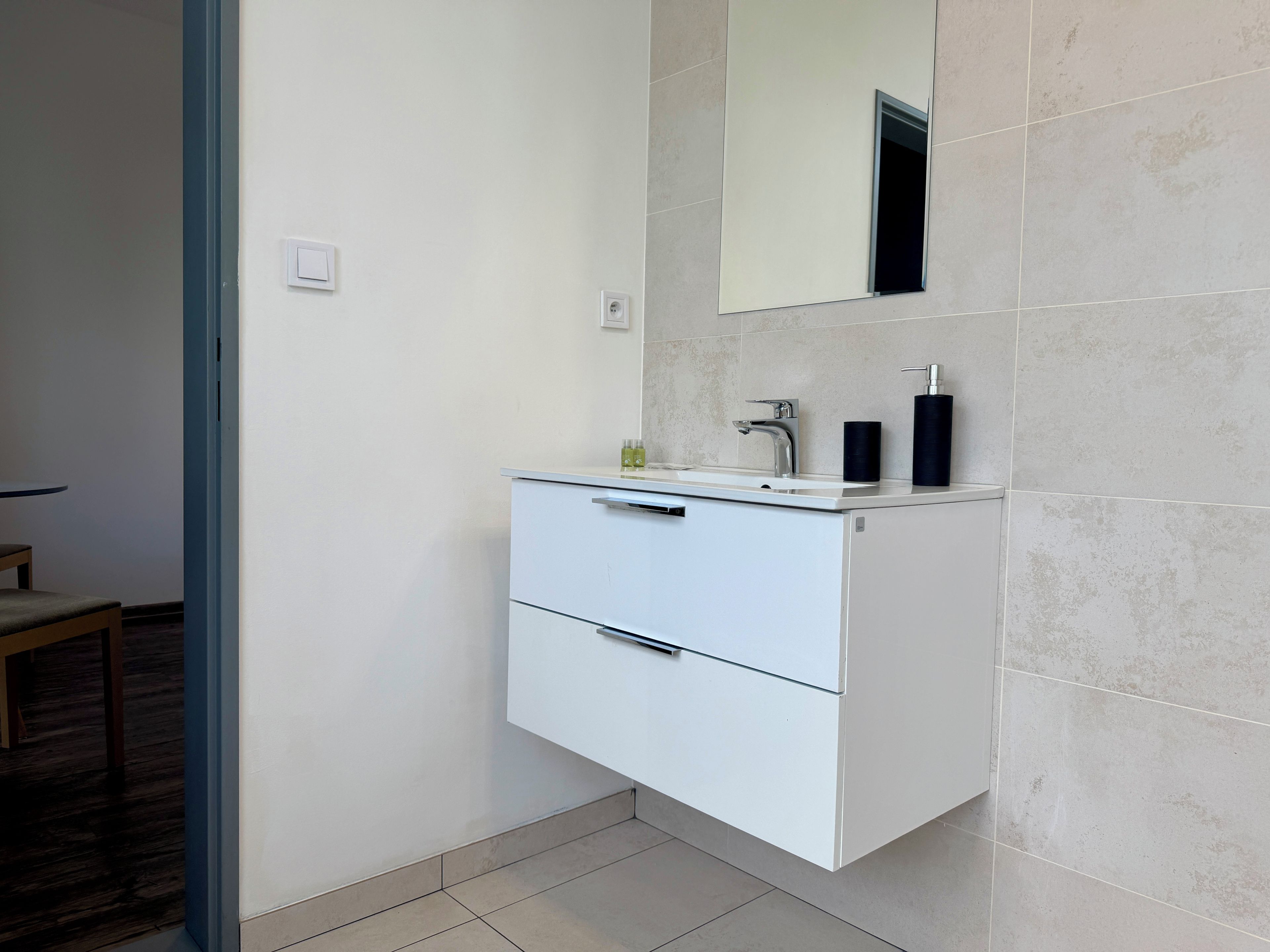 Une salle de bain moderne avec un meuble-lavabo blanc, un miroir, un évier et des toilettes.