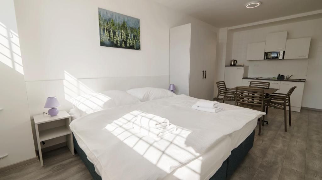 Habitación de hotel con cama, escritorio, silla, mesita, microondas y un cuadro en la pared.