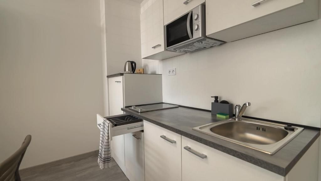 A compact kitchen with a microwave, sink, and a kettle on the countertop.