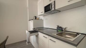A compact kitchen with a microwave, sink, and a kettle on the countertop.