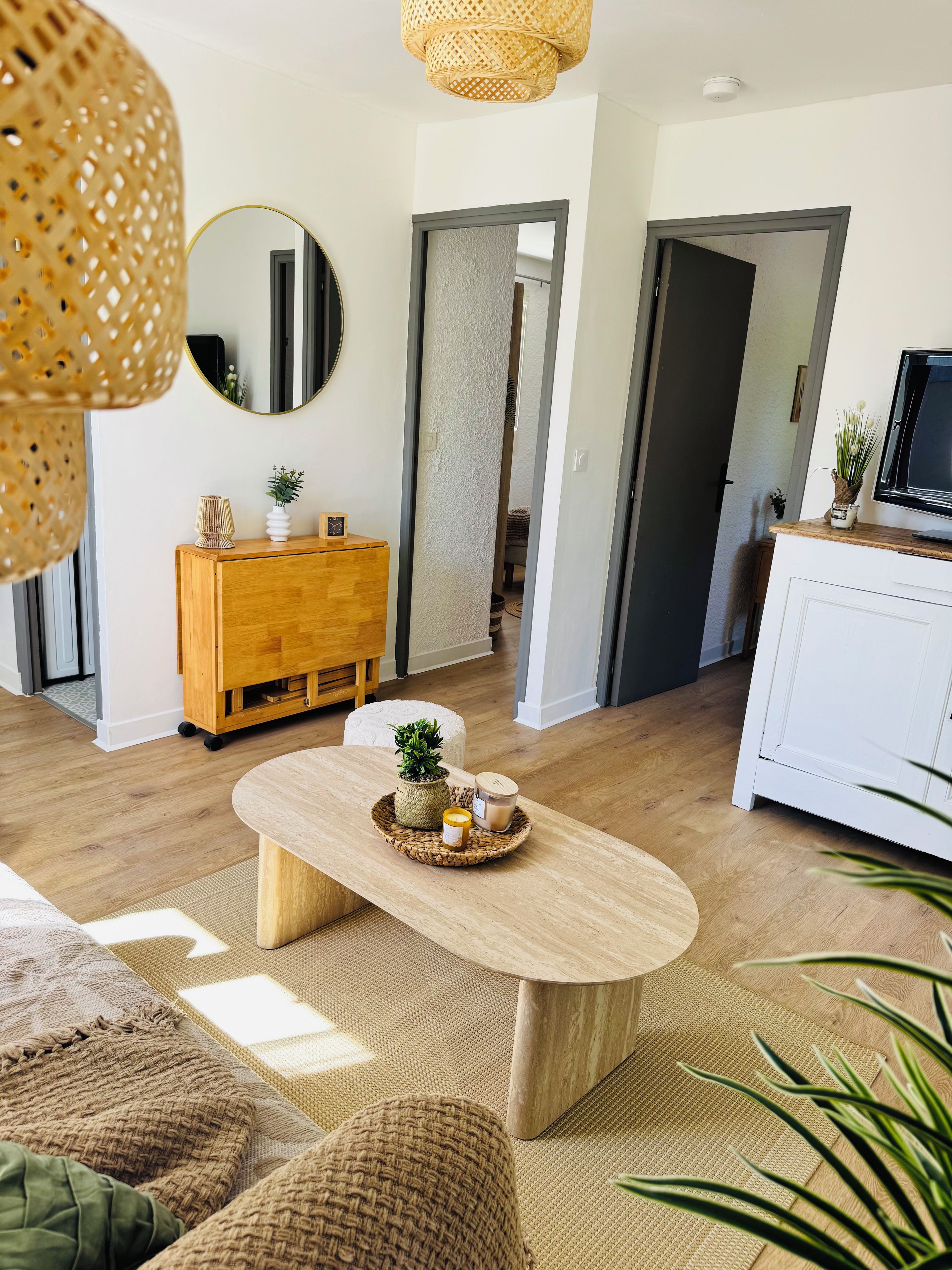 Ein modernes Wohnzimmer mit einem Holztisch, einer weißen Kommode und einer Korbtischlampe.