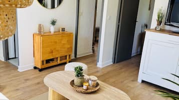 Ein modernes Wohnzimmer mit einem Holztisch, einer weißen Kommode und einer Korbtischlampe.