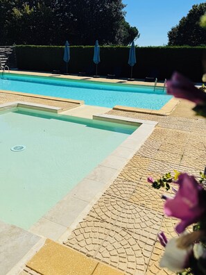 En swimmingpool med ett kaklat poolområde och en häck i bakgrunden.