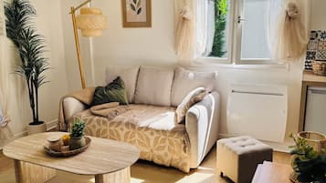 Ein gemütliches Wohnzimmer mit Sofa, Hocker, Couchtisch und Stehlampe.
