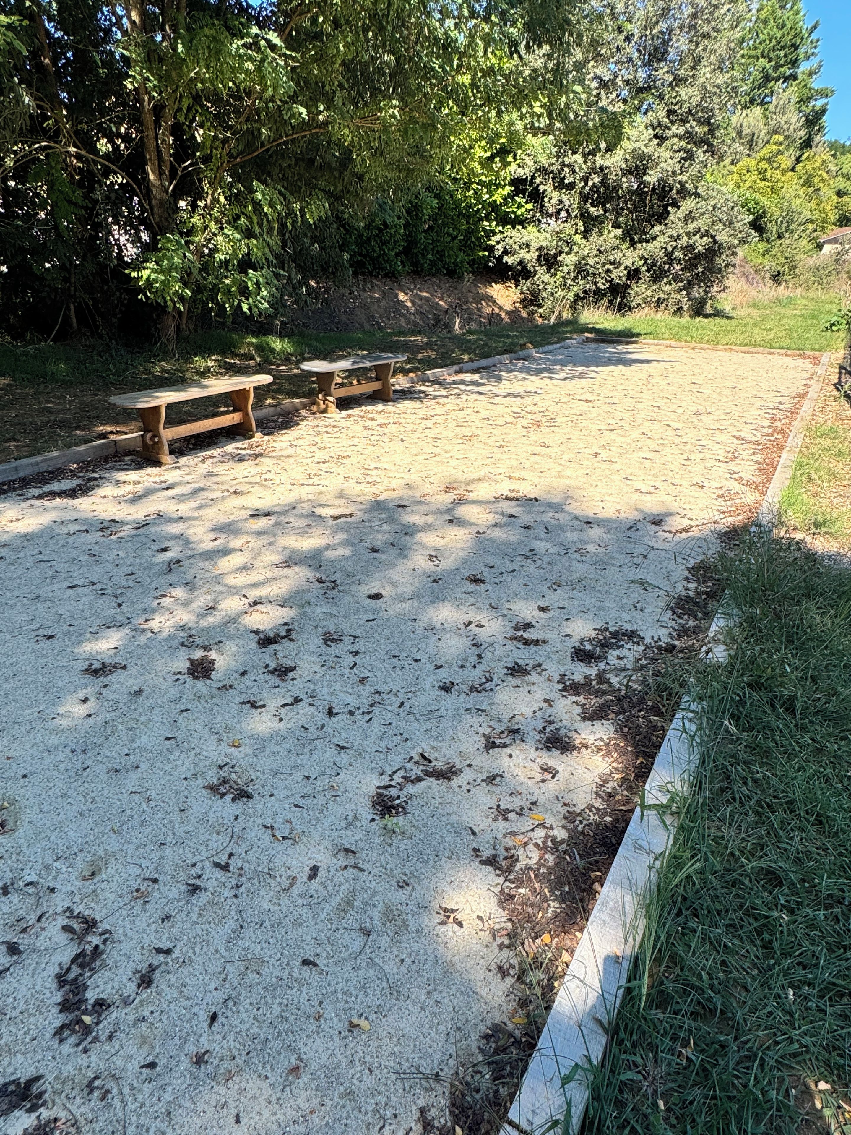 A sandy outdoor area with picnic tables and a grassy border.