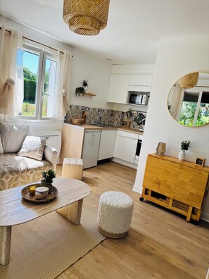 A modern kitchen with white cabinets, a microwave, and a hanging basket.