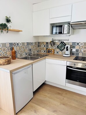 A modern kitchen with white cabinets, a microwave, a coffee maker, and a dishwasher.