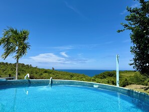 Ein klarer, blauer Himmel, ein Schwimmbecken und Blick auf den Ozean.