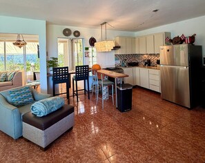 A modern kitchen with a dining area, a sofa, and a view of the outdoors. -  Casa BerKana,  Coastal Home, with OCEAN VIEWS, in charming Quebradillas. (San José)