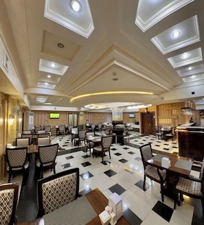 A spacious dining area with multiple tables and chairs, a checkered floor, and a modern ceiling design with recessed lighting. - Hayot Hotel (Tashkent)