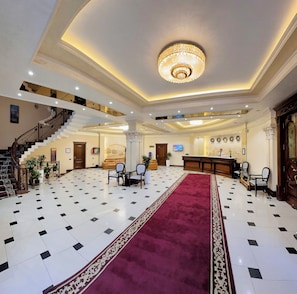 A hotel lobby with a grand staircase, a reception desk, and a chandelier. - Hayot Hotel (Tashkent)
