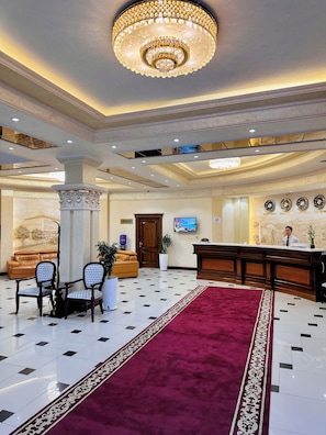 A hotel lobby with a reception desk, seating area, and a chandelier. - Hayot Hotel (Tashkent)