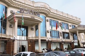 A hotel with a classical facade, multiple flags, and a large entrance. - Hayot Hotel (Tashkent)