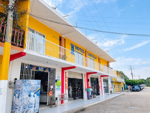 A two-story building with a yellow facade, a balcony, and a sign indicating it is a hotel named 'HOTEL CASTILLO'.
