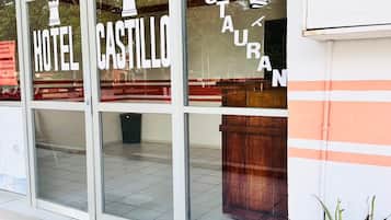 Ein Hotel Eingang mit der Beschilderung 'HOTEL CASTILLO' und einem Schild für 'RESTAURANT', das durch das Fenster sichtbar ist.