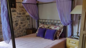 A bed with a canopy, a nightstand, a lamp, and a patterned rug.