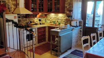 Una cocina rústica con vigas de madera, paredes de piedra y una zona de comedor con una mesa y sillas.