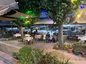 An outdoor dining area with tables and chairs, surrounded by greenery and trees. - Ενοικιαζόμενη βίλλα μέχρι 9 άτομα μια εμπειρία διαμονής στα Καλάβρυτα για δράση (Kleitoria)