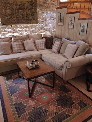 A living room with a beige sectional sofa, a wooden coffee table, and a patterned rug.