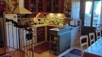 Una cocina con armarios de madera, pared de piedra y ventana con cortinas.