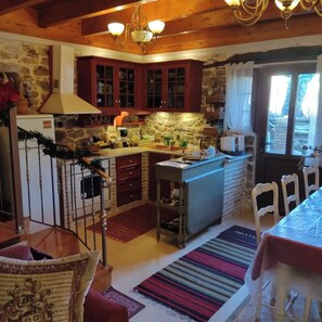 A kitchen with wooden cabinets, a stone wall, and a window with curtains.