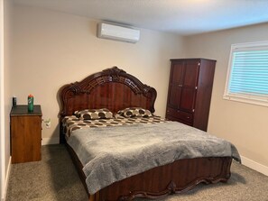 Een slaapkamer met een houten bed, een kledingkast, een klein kastje en een raam met zonwering.