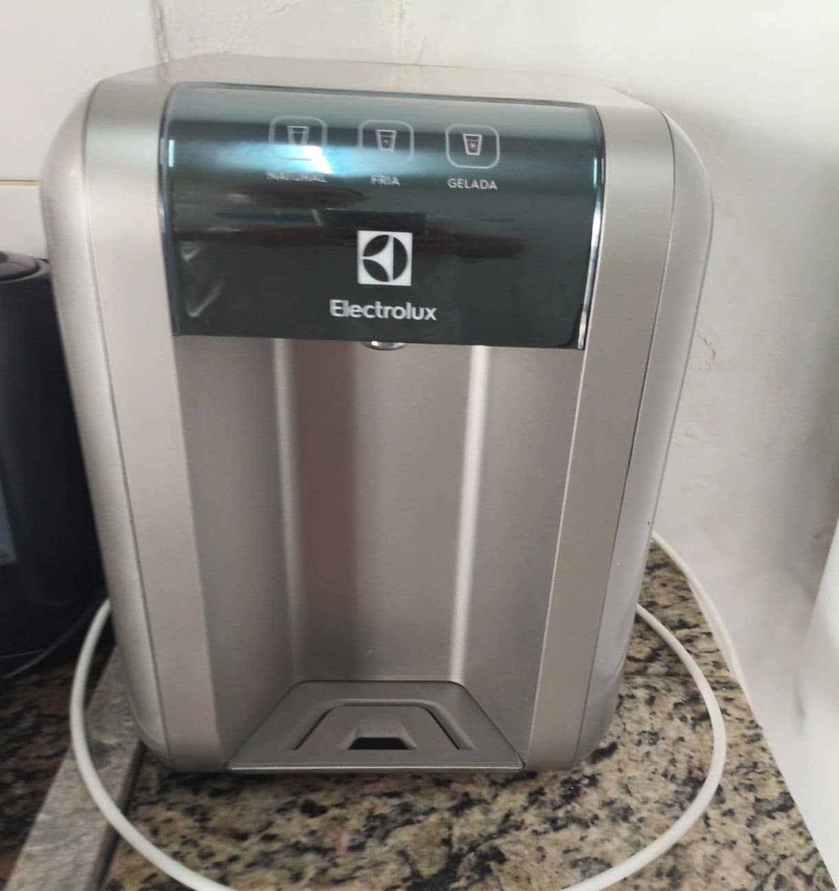 Un dispensador de agua con un panel de control etiquetado 'Electrolux' y opciones para 'FIA', 'FRIA' y 'GELADA'.