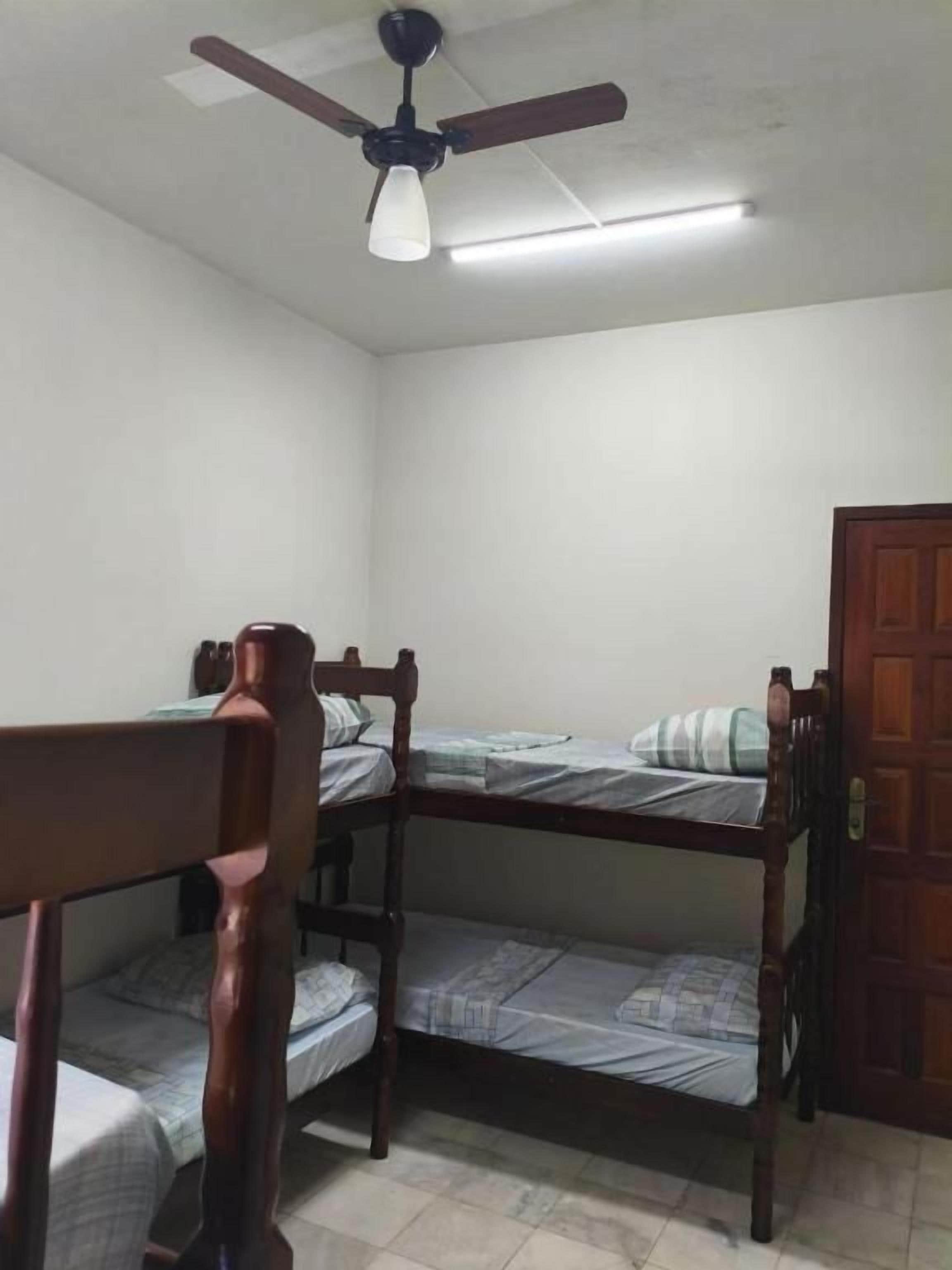 Una habitación con literas, ventilador de techo y una puerta.