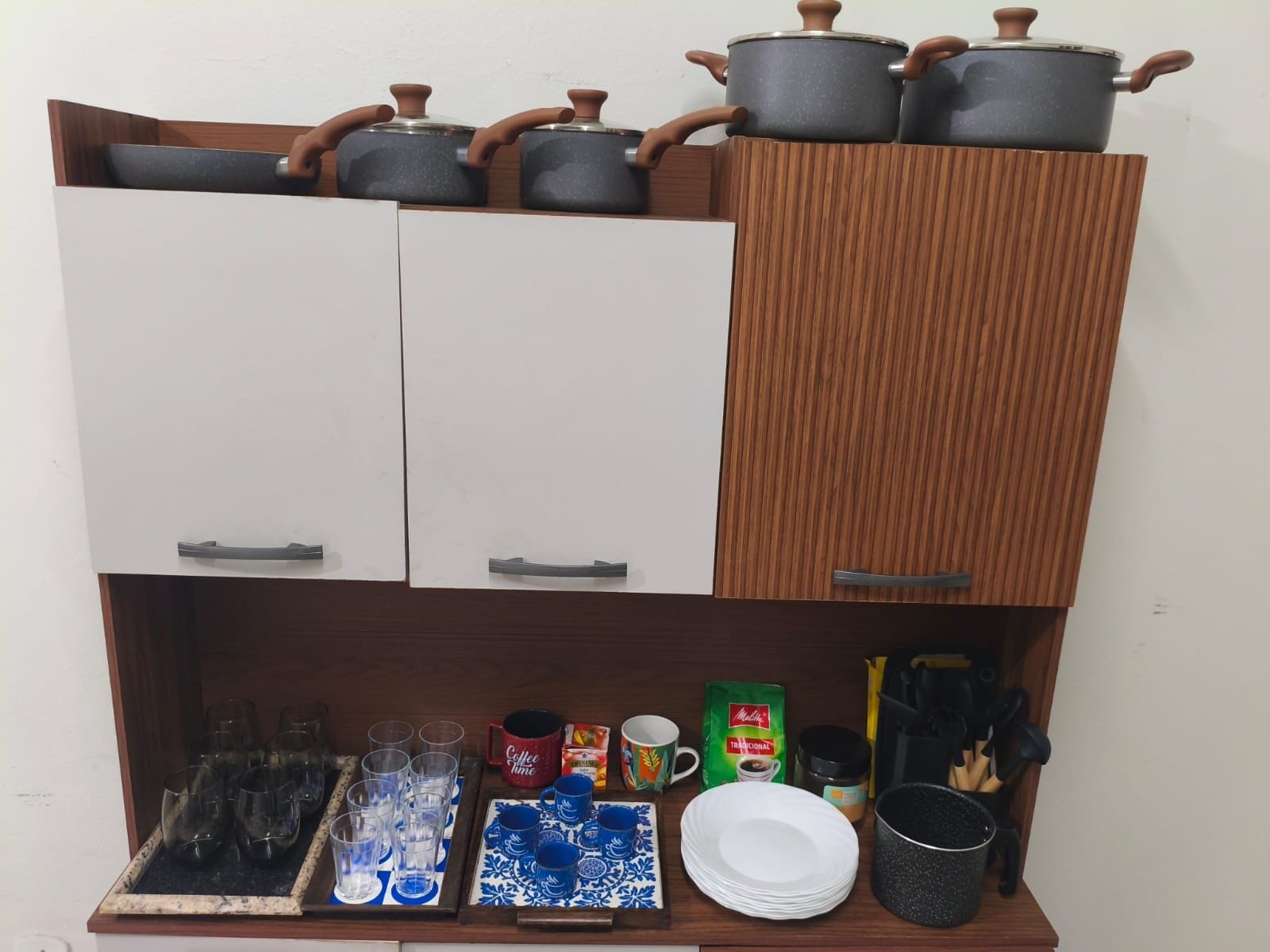 Une cuisine équip ée d’armoires, d’un plan de travail et de divers ustensiles de cuisine, notamment des casseroles, des tasses et des couverts.